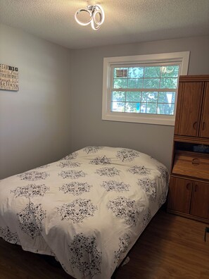 A bedroom with a bed, a window, a wooden cabinet, and a ceiling light fixture. - Wake up to
Lake Erie (Bayham)