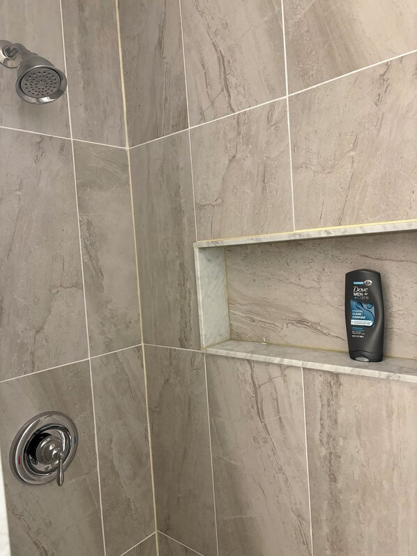 A shower area with a handheld showerhead and a wall-mounted faucet.
