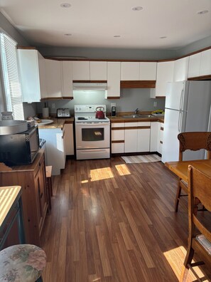 A compact kitchen with white cabinets, a stove, oven, and a refrigerator. - Wake up to
Lake Erie (Bayham)