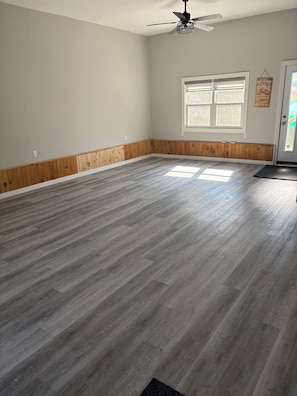 A spacious room with a wooden floor, a ceiling fan, a window, and a door. - Wake up to
Lake Erie (Bayham)