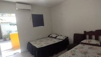 A room with two beds, a window, and an air conditioning unit.