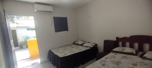A room with two beds, a window, and an air conditioning unit.