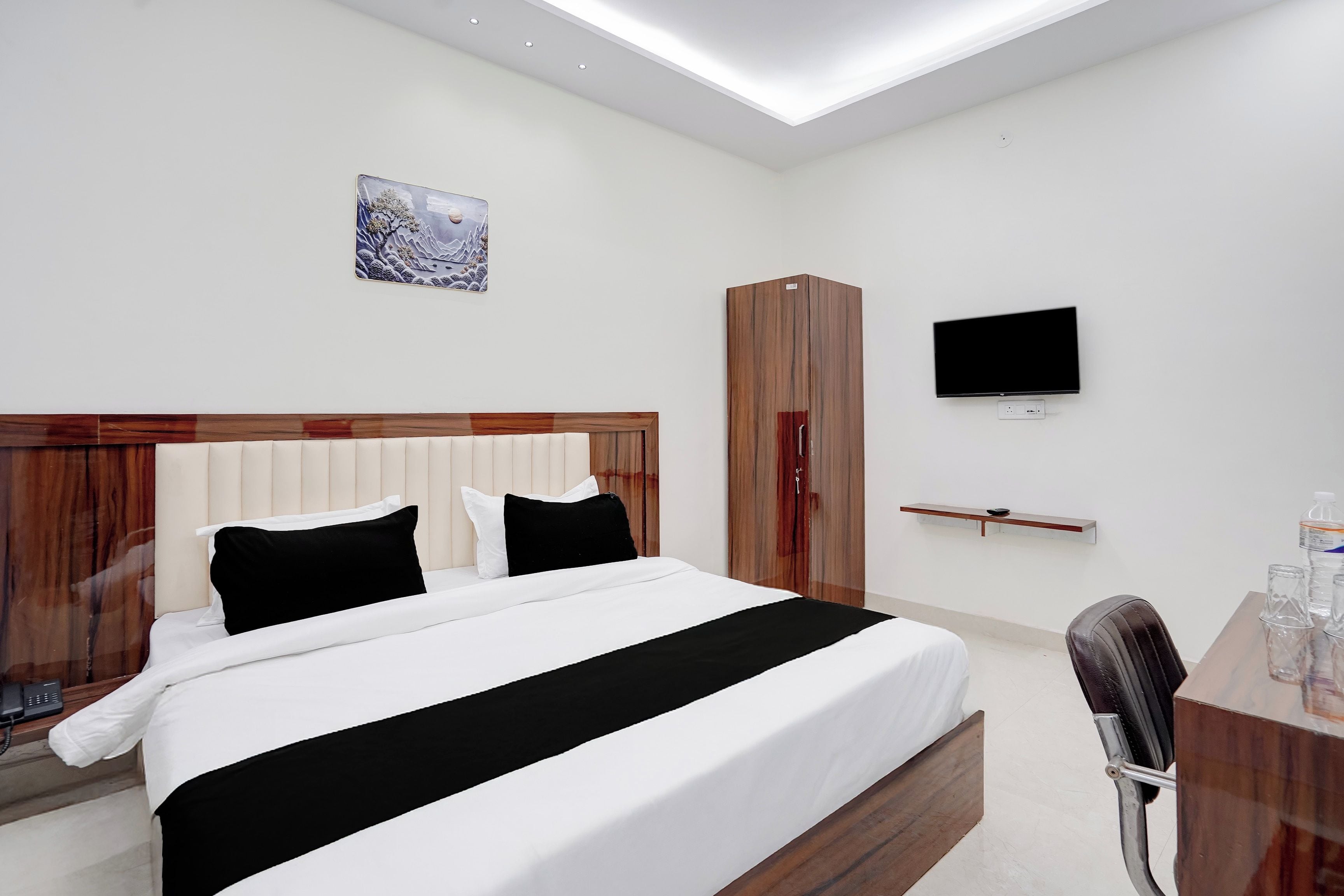 Una habitación de hotel moderna con una cama grande, televisor, armario y escritorio con silla.