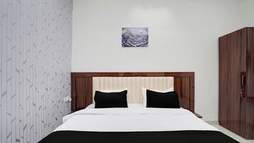 A bedroom with a bed, a headboard, a wardrobe, and a wall-mounted picture.