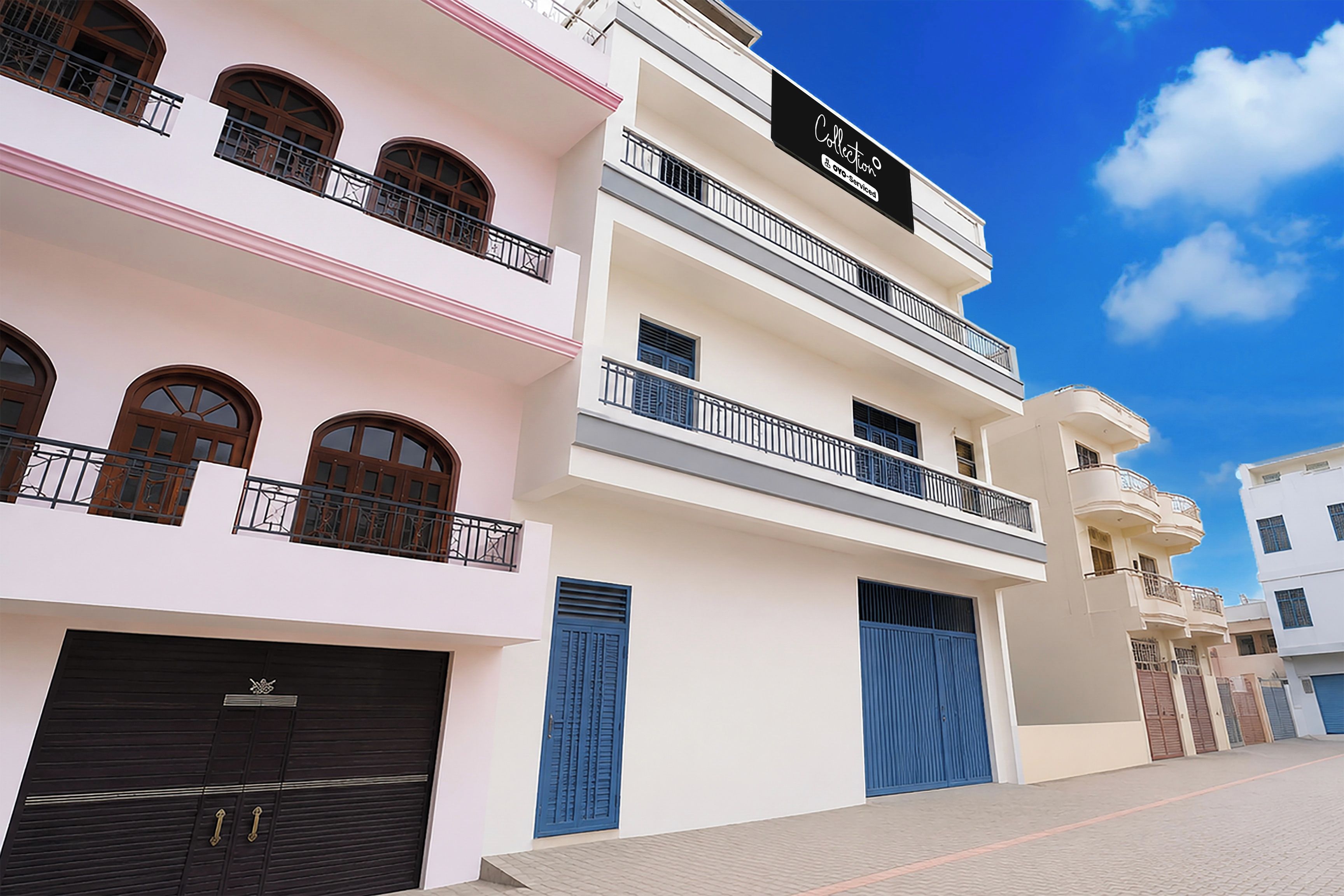 Un immeuble à plusieurs étages doté de balcons, d’un garage et surplombant un ciel dégagé.
