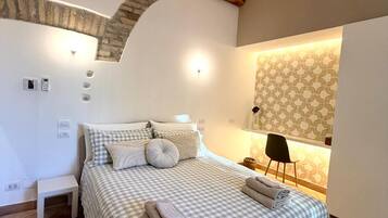 A bedroom with a checkered bedspread, a bedside table, a chair, and a patterned wall.