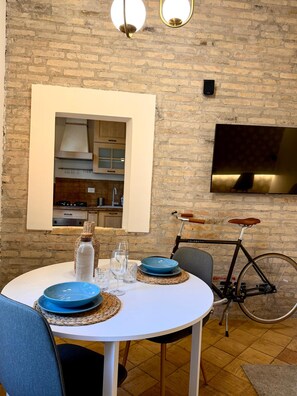 Un coin repas avec un mur en briques, un téléviseur fixé au mur et un vélo.