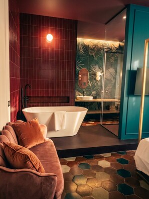 A modern bathroom with a freestanding bathtub, a mirror, and a sink. - Living Room 18 Queen Deluxe (ROMA)