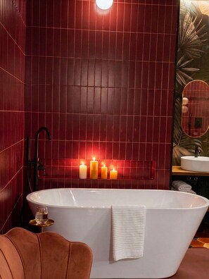 Ein Badezimmer mit einer freistehenden Badewanne, einem Spiegel und einem Handtuchhalter.