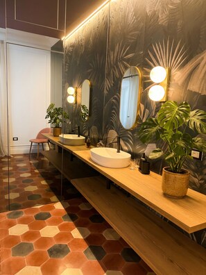 Ein modernes Badezimmer mit einem großen Spiegel, zwei runden Lampen, einem Waschbecken und einer Sitzbank.