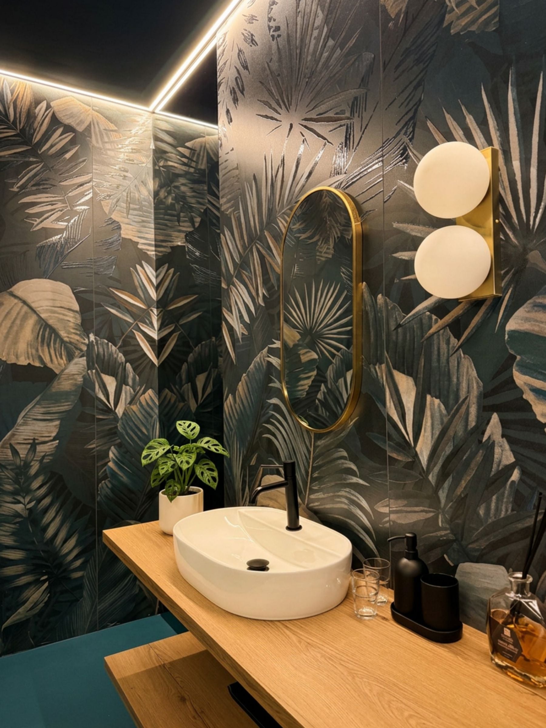 Un bagno con un lavandino tondo, uno specchio e una pianta in vaso.