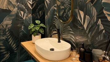 Un bagno con un lavandino tondo, uno specchio e una pianta in vaso.