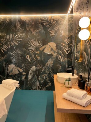 Un bagno con uno specchio grande, un lavandino e degli asciugamani.