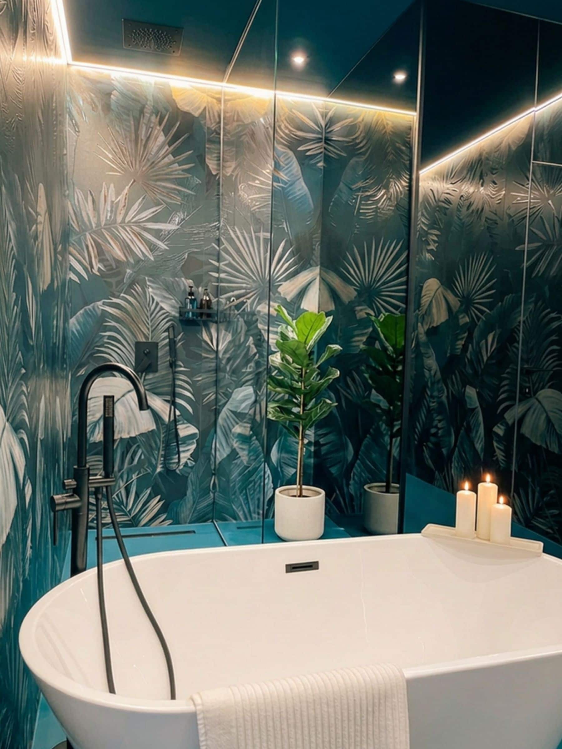 Un bagno moderno con una vasca freestanding, una pianta in vaso e uno specchio con motivo a foglia tropicale.