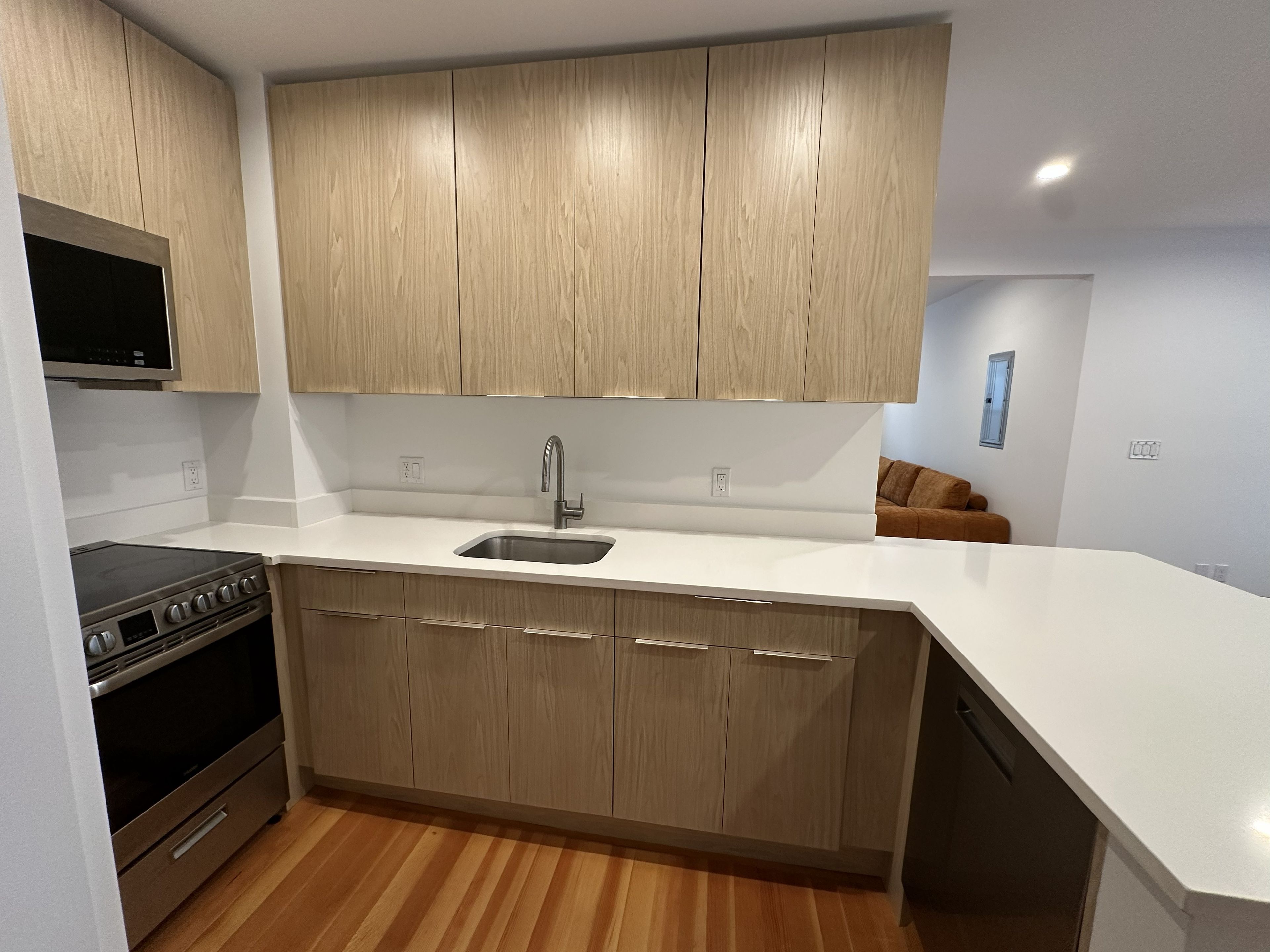 A modern kitchen with wooden cabinets, a stainless steel sink, and a built-in oven.