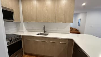 A modern kitchen with wooden cabinets, a stainless steel sink, and a built-in oven.