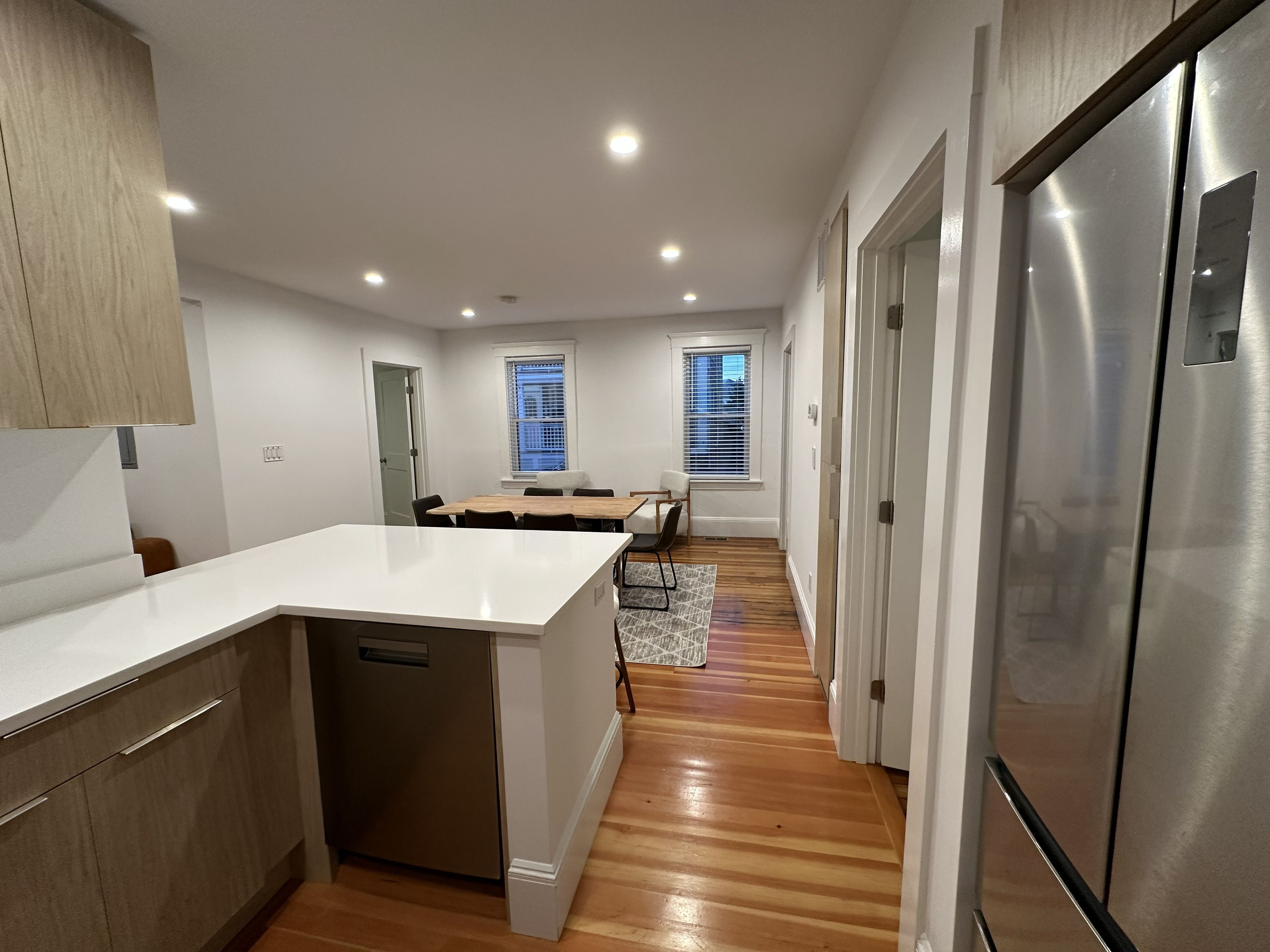 A modern kitchen with a central island, stainless steel appliances, and a wooden floor.