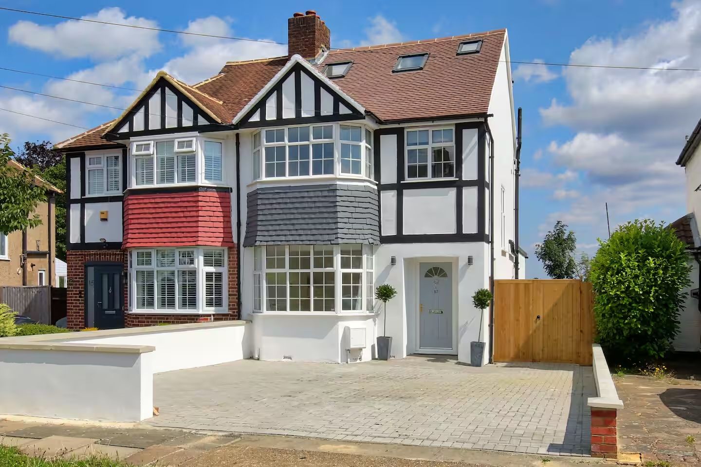 A two-story house with a bay window, a red brick section, and a white facade.
