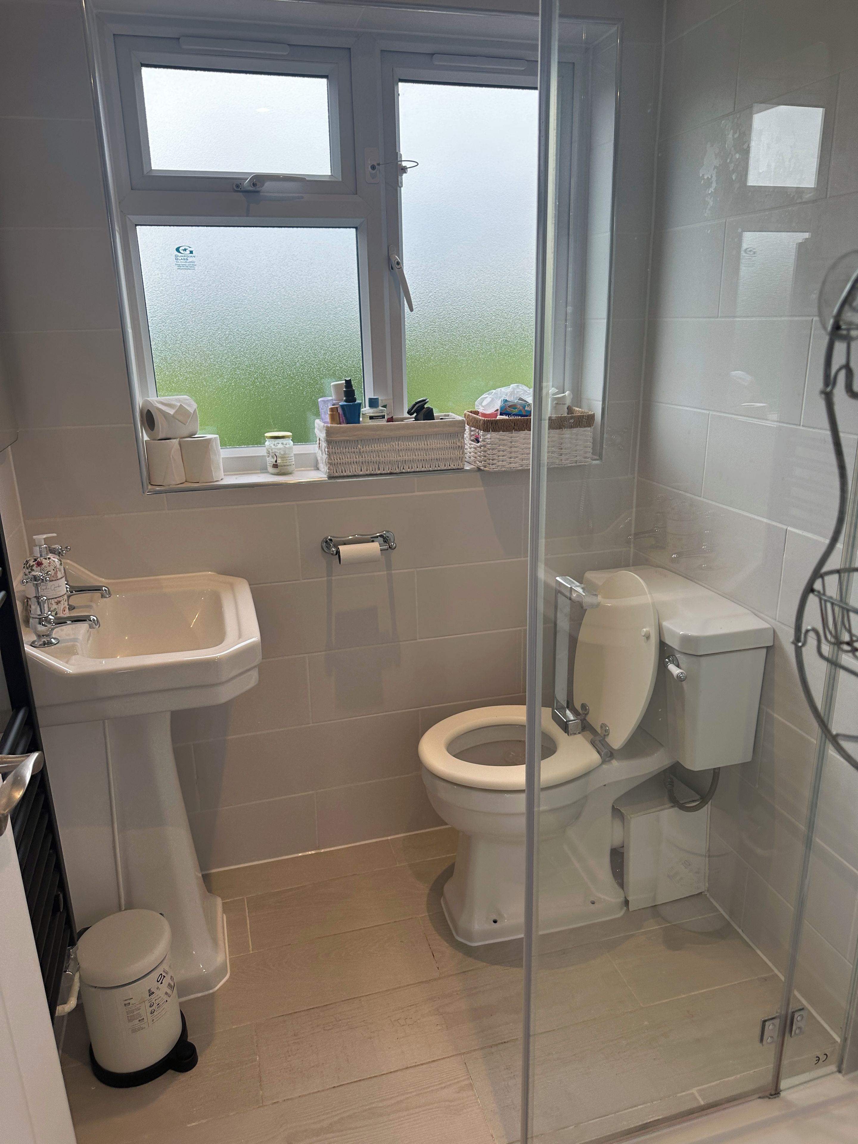 A bathroom with a toilet, sink, and a window with a view.