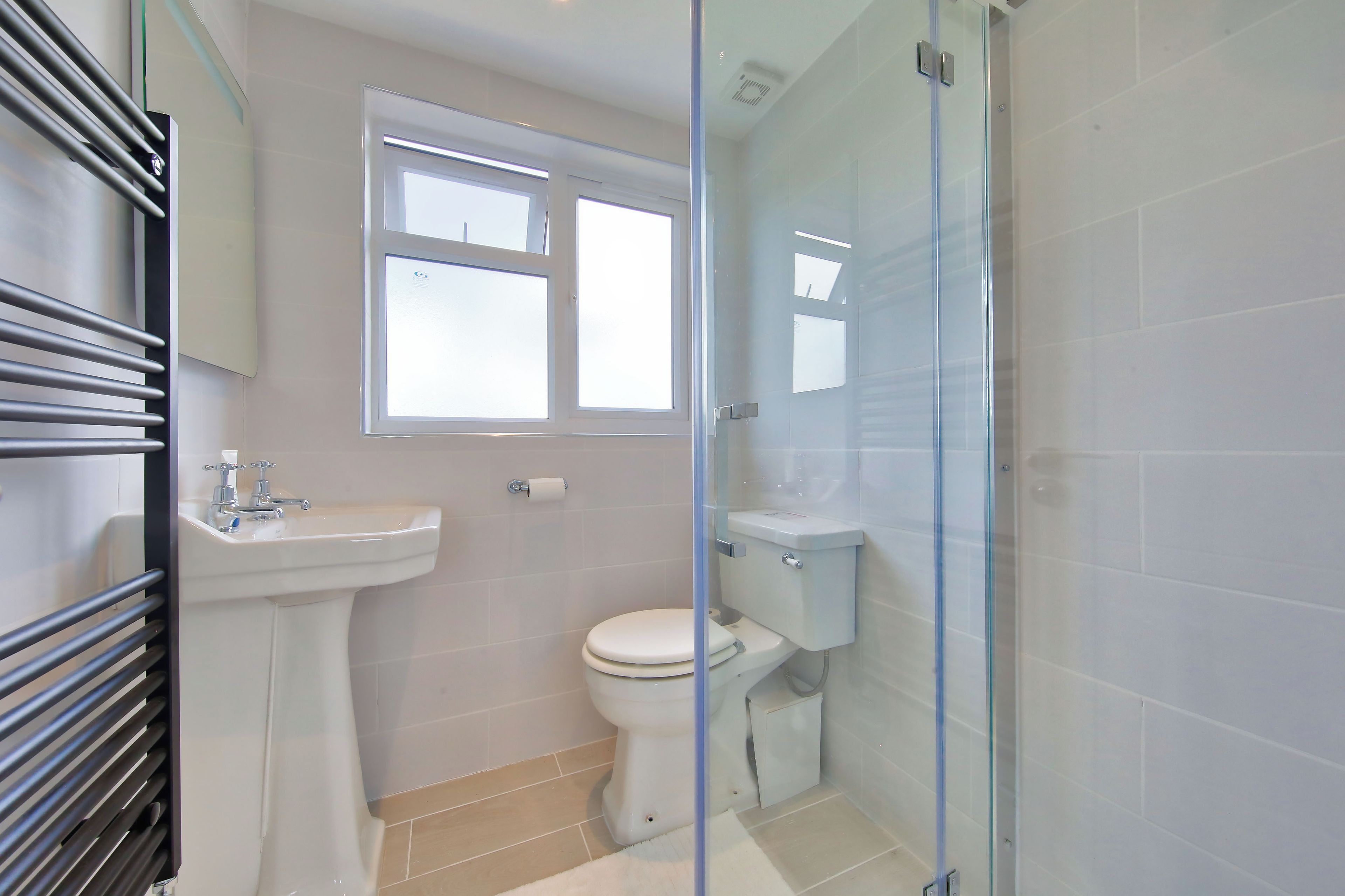 A bathroom with a toilet, sink, and a glass shower enclosure.