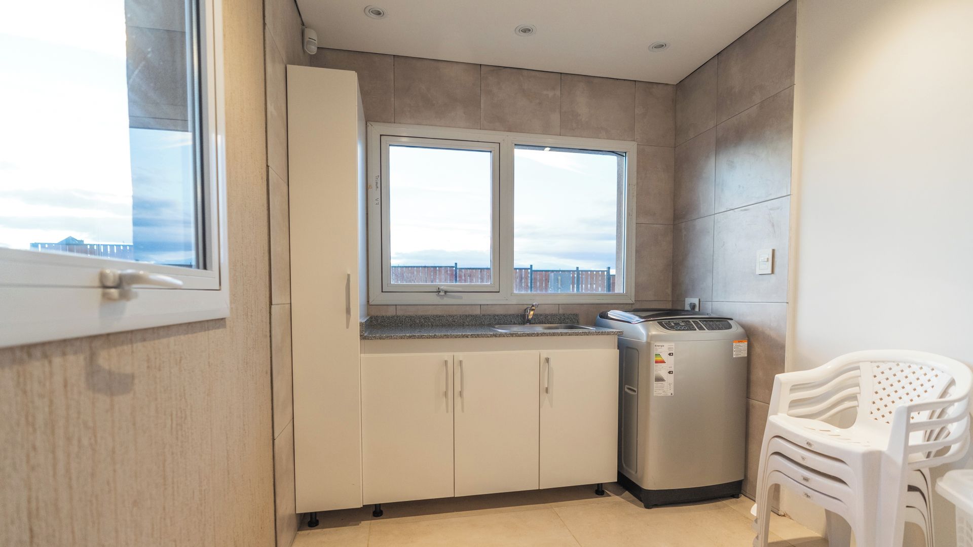 Una cocina funcional con ventana, un refrigerador y una silla.