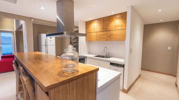 Une cuisine moderne dotée d’un îlot central, de meubles de rangement en bois intégrés et d’une hotte en acier inoxydable.