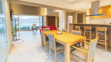Un comedor moderno con una mesa y sillas de madera, una cocina con armarios de madera, y vistas al exterior.