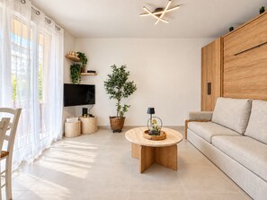 En moderne stue med sofa, sofabord, fjernsyn og potteplanter.