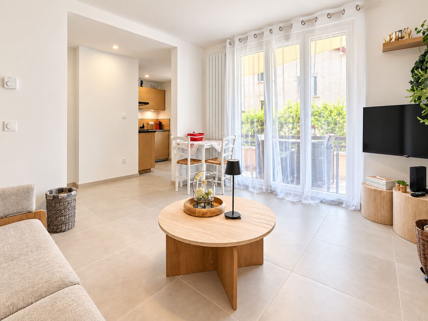 Una sala de estar moderna con una mesa de centro redonda de madera, un sofá, un televisor y un balcón con vistas.