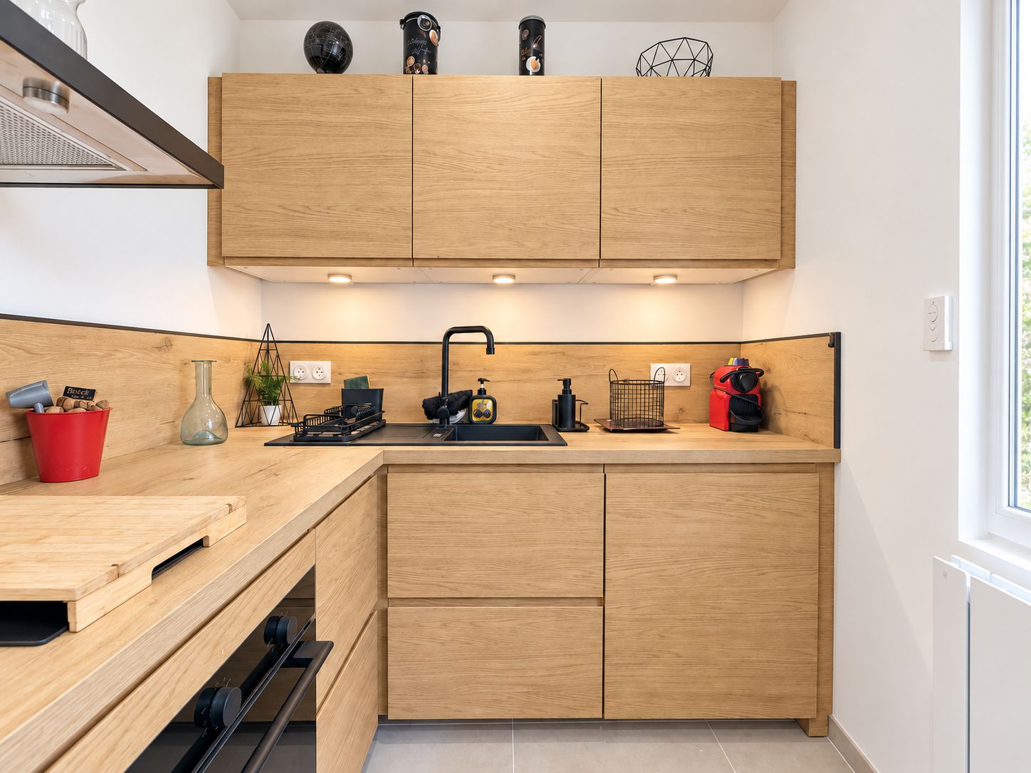 A modern kitchen with wooden cabinets, a black sink, and various kitchen appliances.