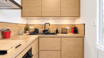 A modern kitchen with wooden cabinets, a black sink, and various kitchen appliances.