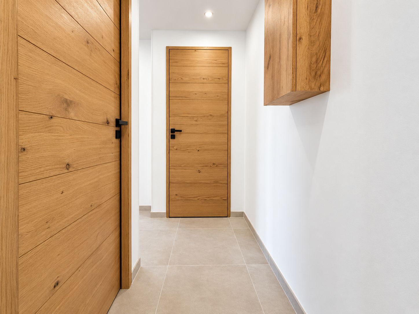 A hallway with wooden doors and a white wall.