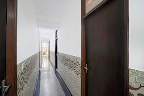 A hallway with patterned walls, a wooden door, and a metal handle. - Super Townhouse Sector 13 Gurgaon (Gurugram)