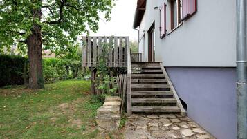 A stone staircase leading to a wooden door, surrounded by a grassy lawn and a tree.