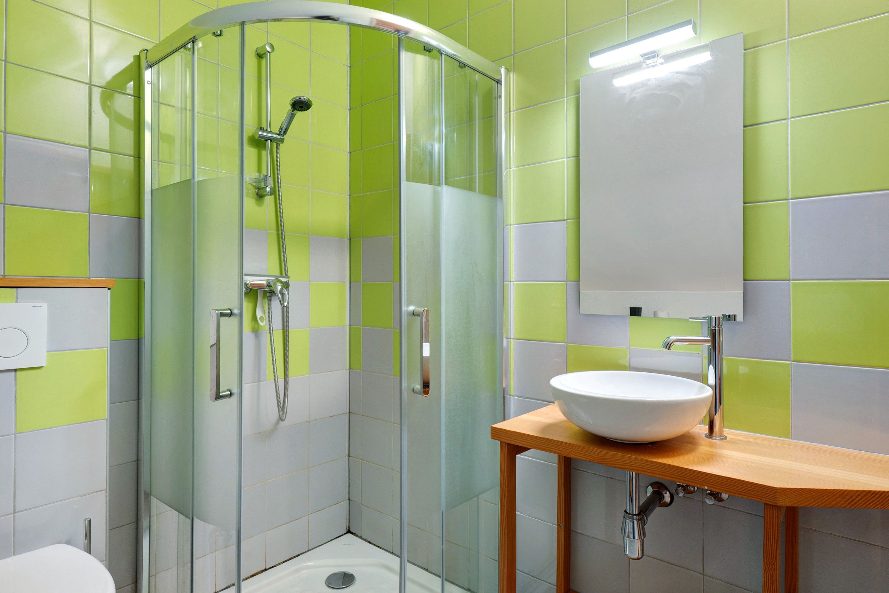 Un baño moderno con ducha acristalada, un lavabo blanco y un espejo sobre él.