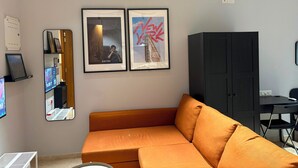 Uma sala de estar moderna com sofá, quadros, armário e escrivaninha.