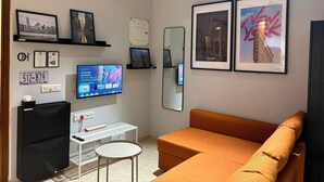 Uma sala de estar moderna com televisão de tela plana, um sofá e quadros nas paredes.