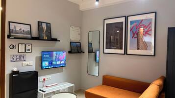 A modern living room with a flat-screen TV, a sofa, and framed pictures on the wall.