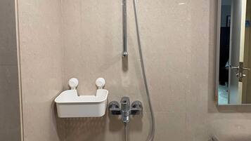 A bathroom with a shower, a sink with a mirror, and a toilet.