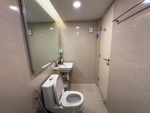 A compact bathroom with a toilet, sink, and mirror. - Hiranandani Estate_New York Studio_WiFi (ठाणे)