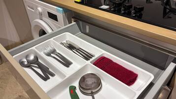 Un cajón de cocina con utensilios, un colador y una toalla roja.