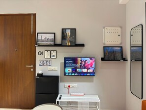 Habitació amb televisió que mostra una pel·lícula, una porta i una taula petita amb un comandament a distància.