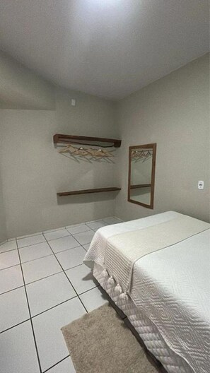 Een slaapkamer met een bed, een spiegel en twee planken.