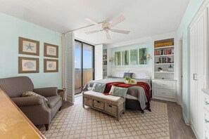 A bedroom with a bed, a chest of drawers, a bookshelf, a ceiling fan, and a view through a glass door. - Arcadian II 10F 3BR Condo in Shore Drive (Myrtle Beach)