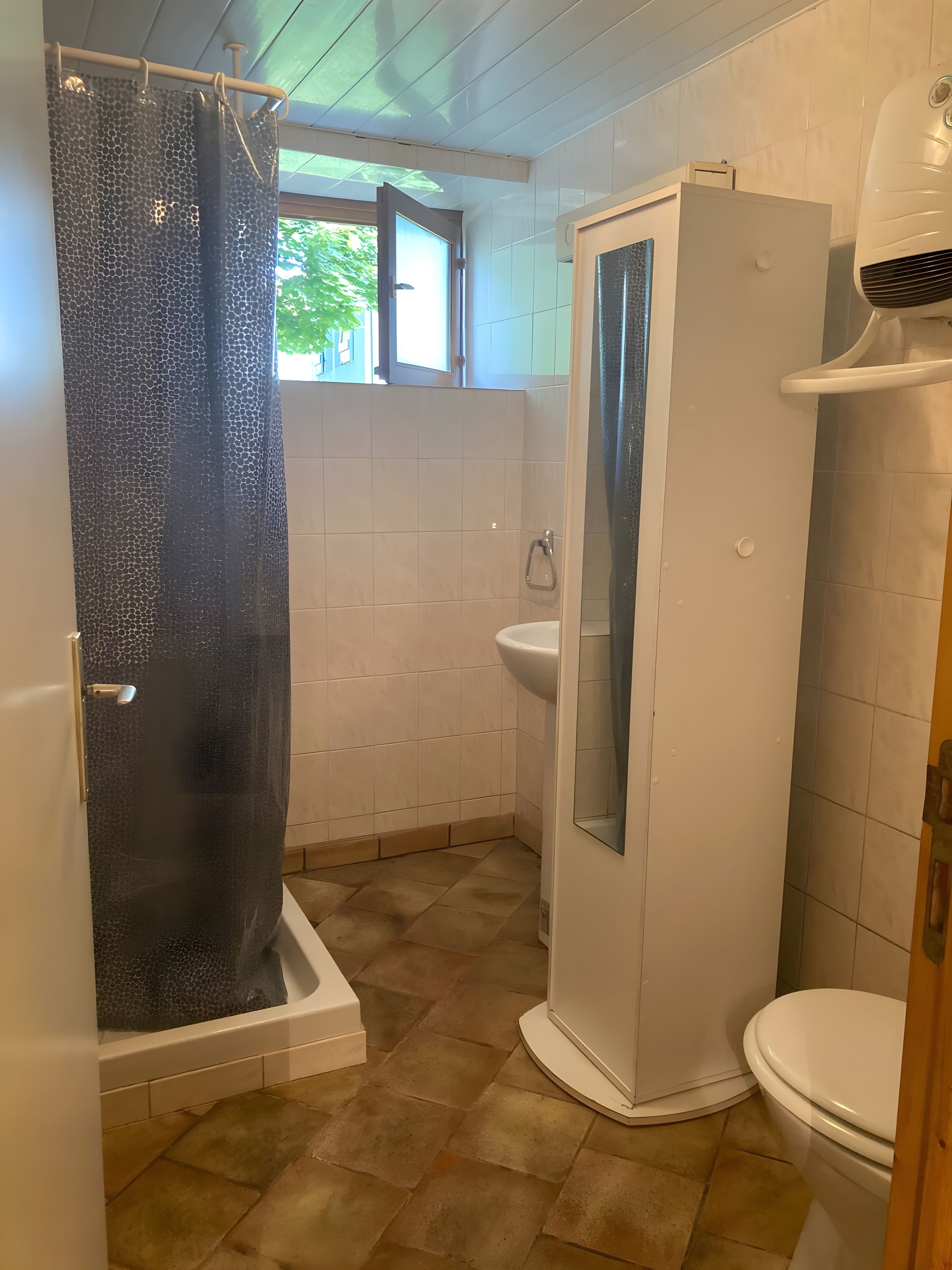 Een badkamer met douche, toilet en wastafel.