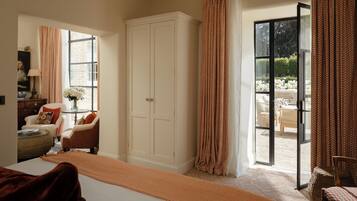 A spacious bedroom with a large bed, a wardrobe, and a view of the garden through a sliding glass door.