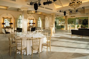 A formal dining room with a round table set for a meal, surrounded by chairs.