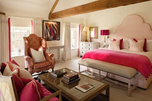 A bedroom with a large bed, a chair, a bedside table, and a bookshelf.