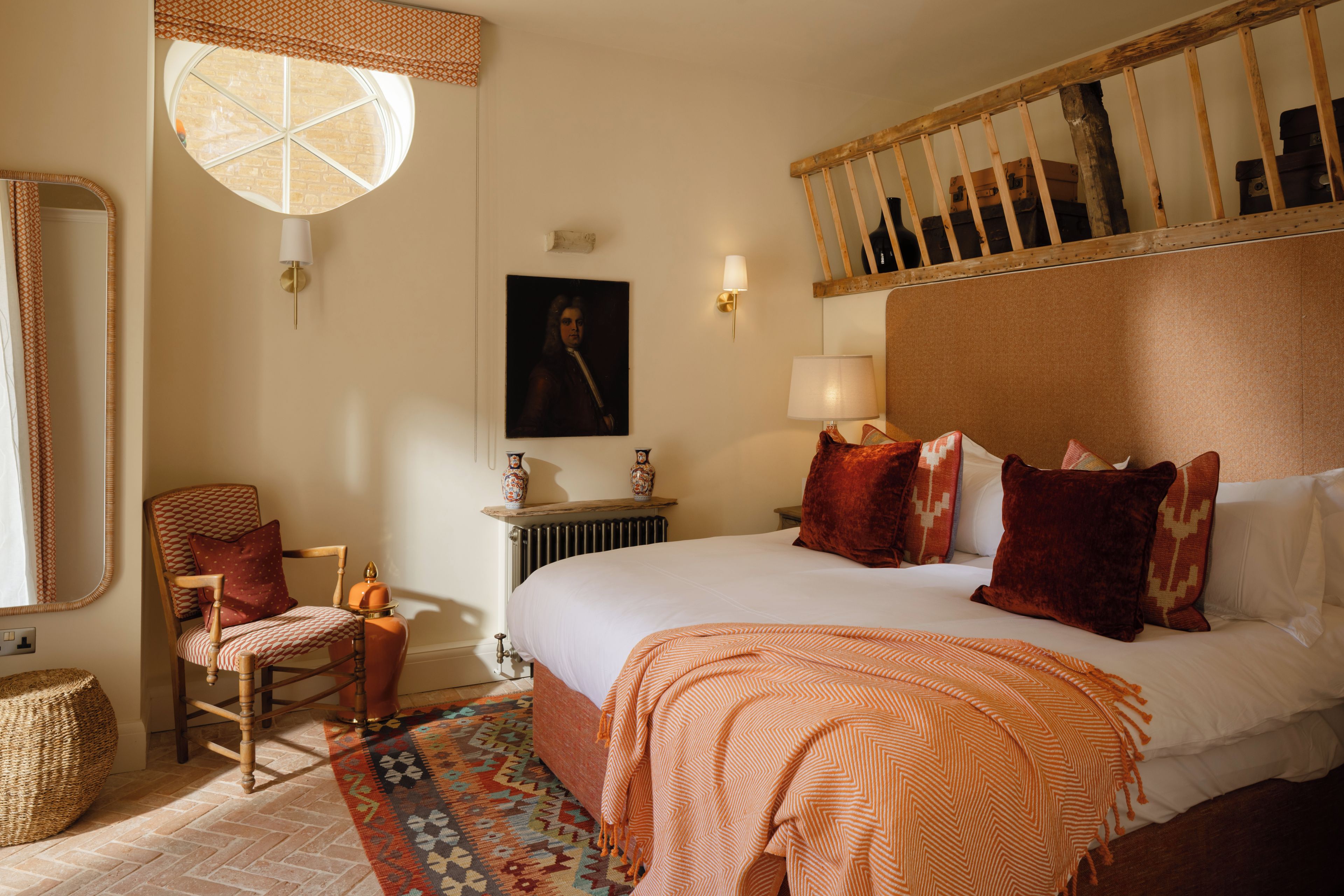 Habitación de hotel con una cama grande, una silla, una mesita, un espejo y un ventanal con vistas al exterior.