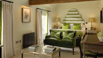 Una habitación con una cama, un sofá verde, una mesa de centro de vidrio y un radiador.